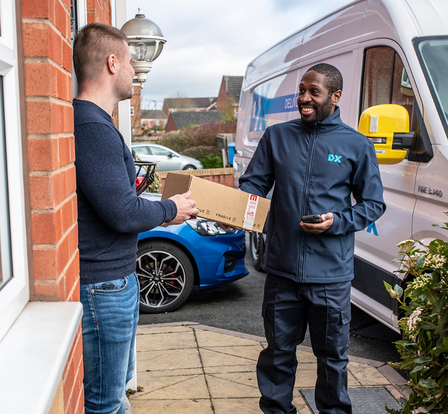 Dx Delivery driver giving customer a parcel on the doorstep